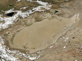 Foto de la NASA de la cuenca del Tarim; el río es el contorno superior e izq. de la zona gris del centro. Al centro izq. su afluente el Hetianhe.