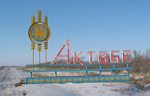 Escudo de Aktobe en al borde de una ruta en el confín de la ciudad