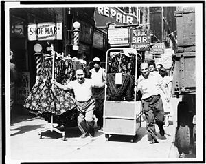 Hombres halando pacas de ropa en una acera atestada en Garment District (1955)